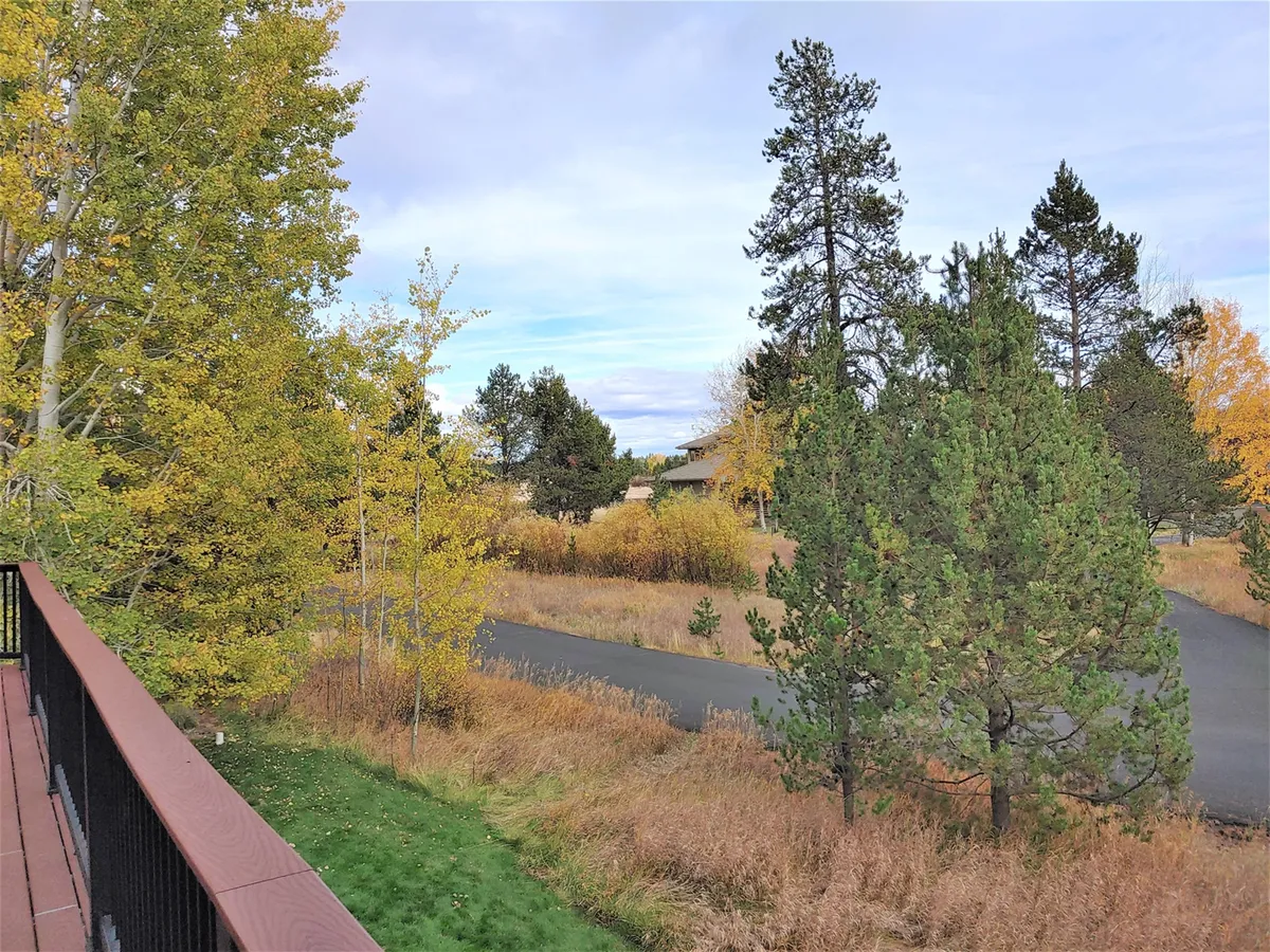 A scenic exterior view showing colorful trees, a road, and distant homes—evoking the extensive walking and biking trails described in the section. The tranquil setting suggests opportunities for nature exploration and family outings right outside the front door.