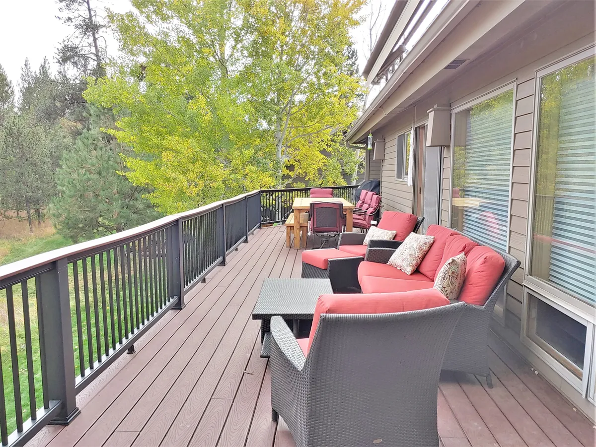 This exterior image features a comfortable outdoor seating and dining area surrounded by lush greenery, offering inviting views that connect the home to its scenic natural surroundings. The space is ideal for relaxing, entertaining, or simply enjoying the outdoors—environments that resonate with the sense of arrival and exploration for aviators.