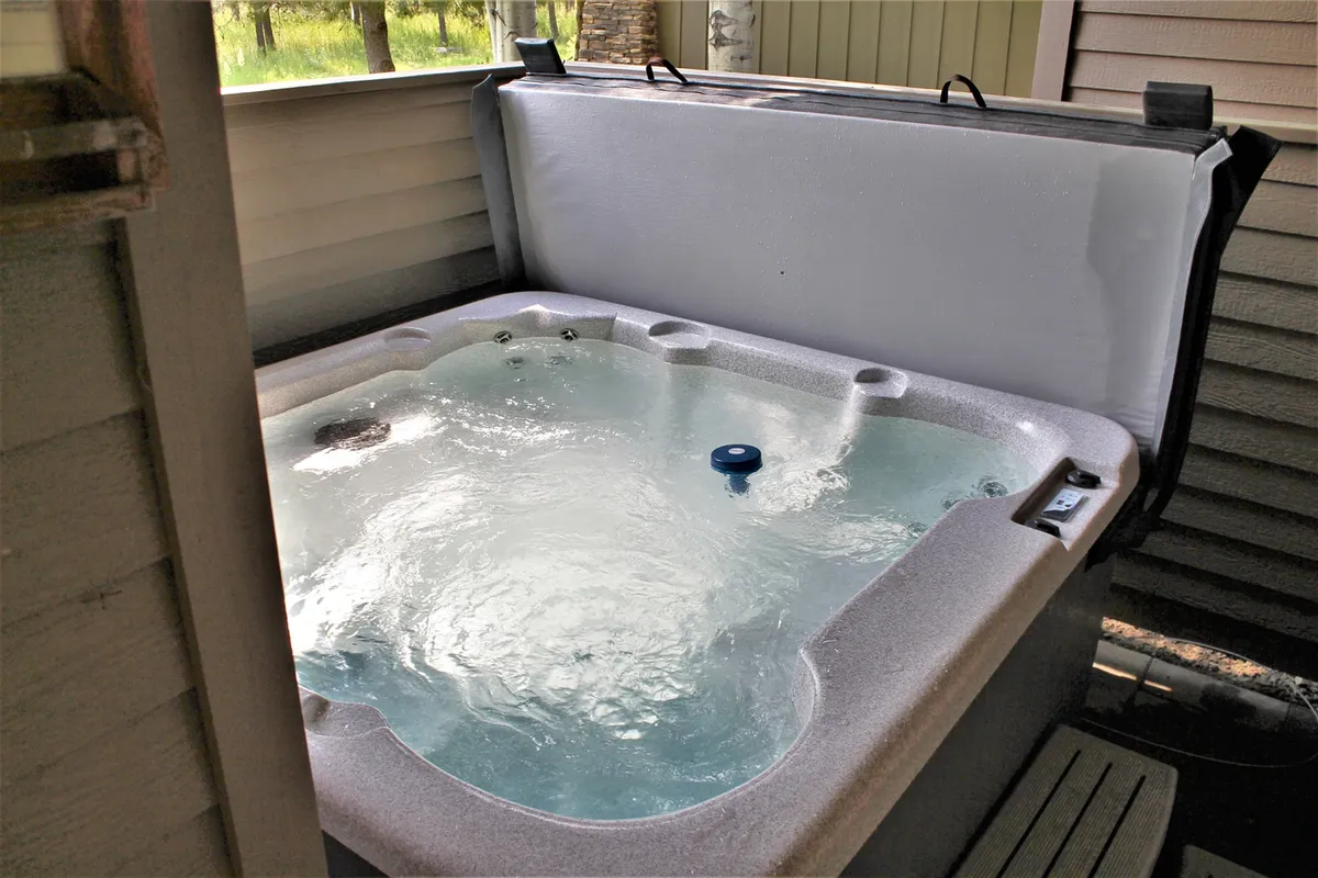 A tranquil hot tub nestled among lush greenery, inviting guests to relax and unwind after a day of adventure. The hot tub is positioned to offer privacy while still feeling surrounded by nature, with space for several people to enjoy the experience together.