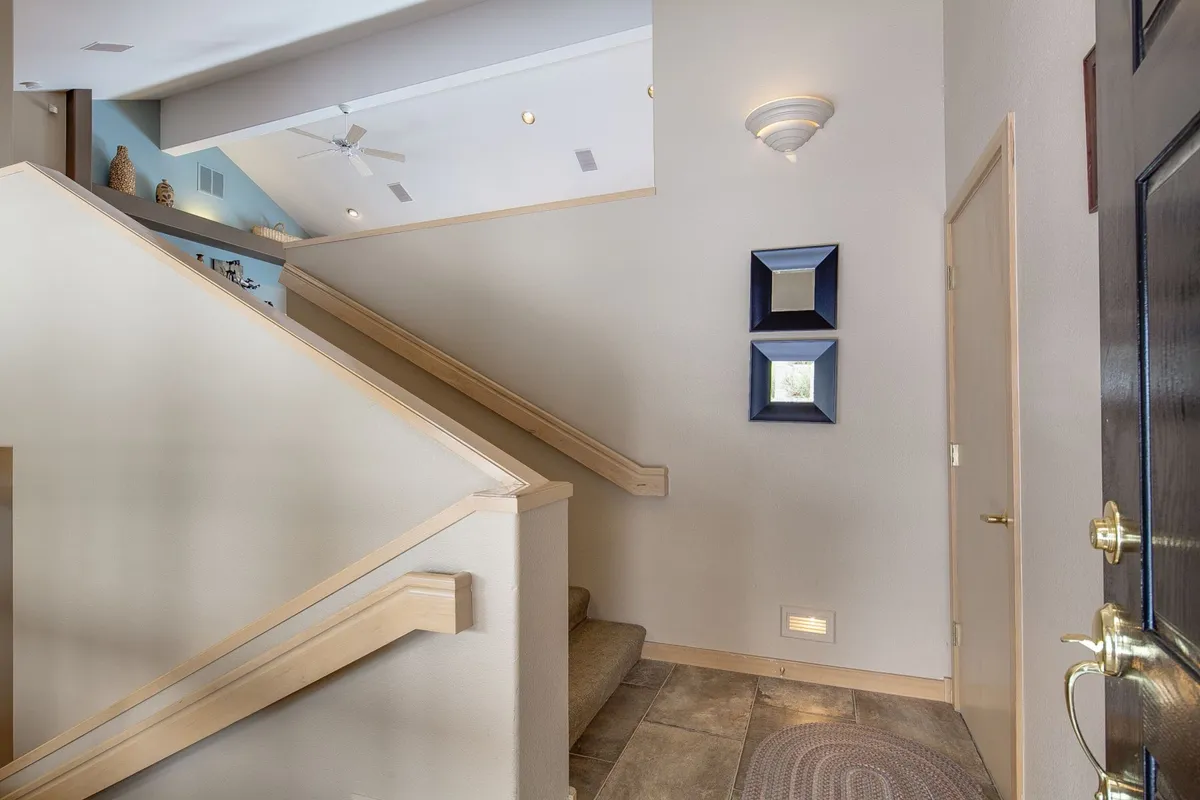 A bright and inviting entryway featuring a staircase, mirrors, and the front door, creating a welcoming first impression. The space is styled to greet guests and signals the transition from home comfort to adventures just outside the threshold.
