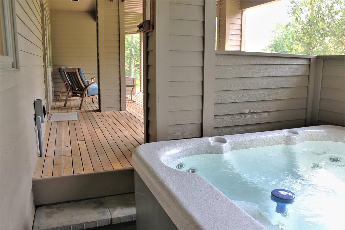 An inviting hot tub on a wooden deck, accompanied by a cozy outdoor seating area. The space is designed for both relaxation and socializing, offering sunset views and a seamless flow between indoor comfort and outdoor living.
