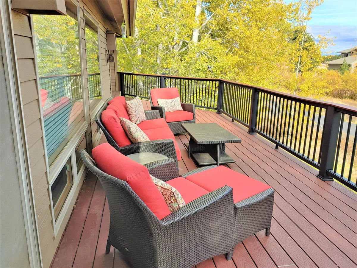 A comfortable outdoor seating area arranged for relaxation against the backdrop of surrounding nature. The setup includes red cushioned seats and a black table, with views that suggest connection to the outdoors and opportunities for enjoying the scenery at different times of day.