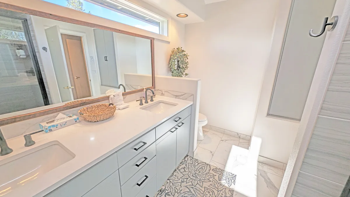A modern bathroom featuring a double sink vanity, large mirror, textured tiles, and a spacious shower area. The overall ambiance is fresh and rejuvenating, ideal for morning or evening routines.